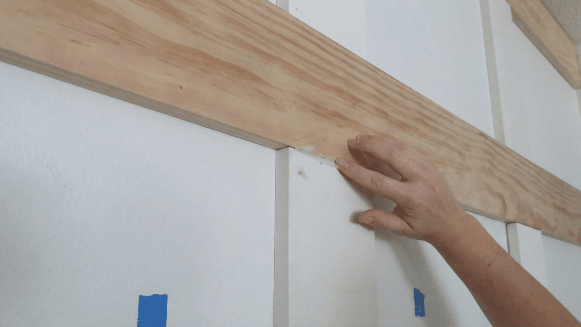 person applying wood filler to the seam of a wooden board on the wall