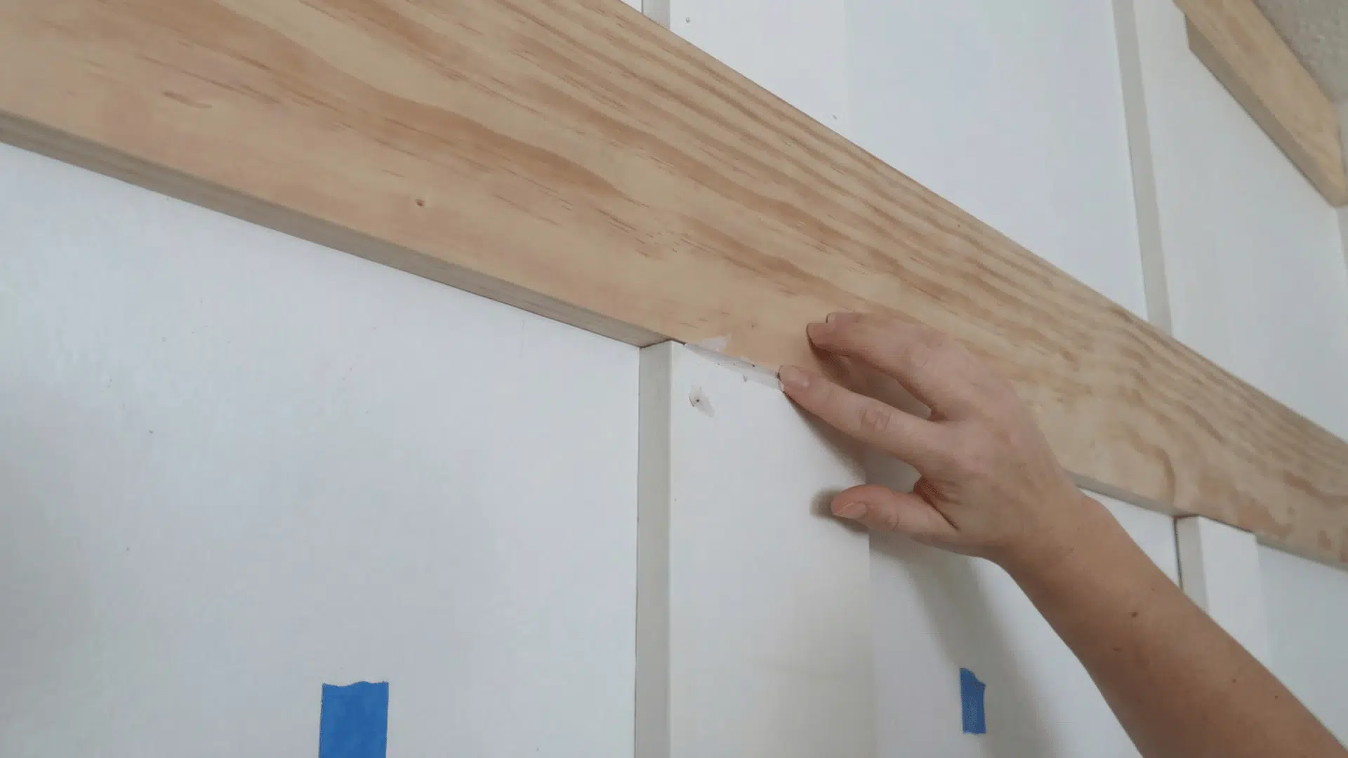 person applying wood filler to the seam of a wooden board on the wall