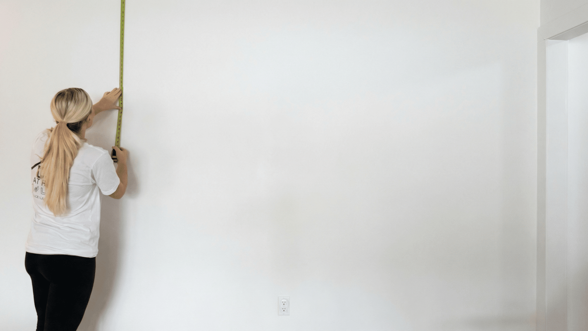 person measuring a wall with a tape measure