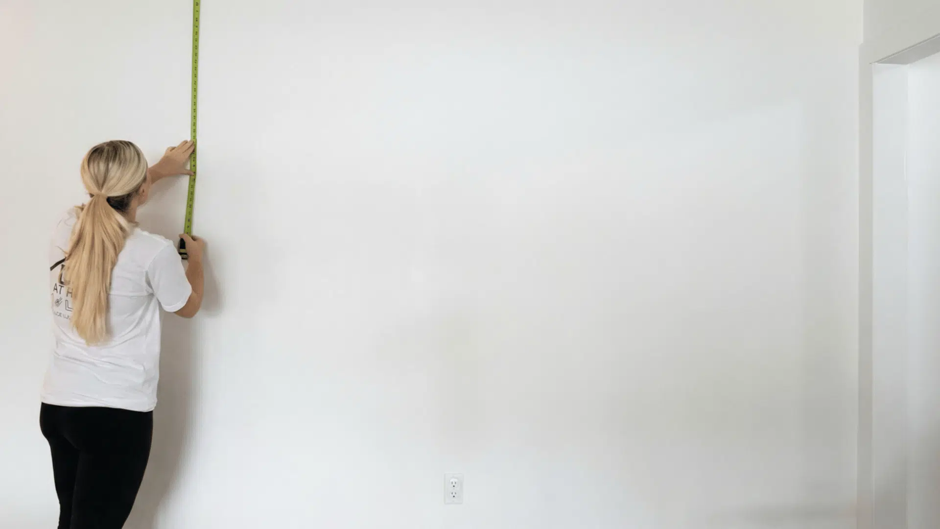 person measuring a wall with a tape measure