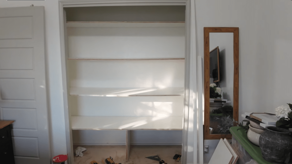 person positioning wooden support board on wall, aligning and pressing it into place before fastening for closet shelving structure