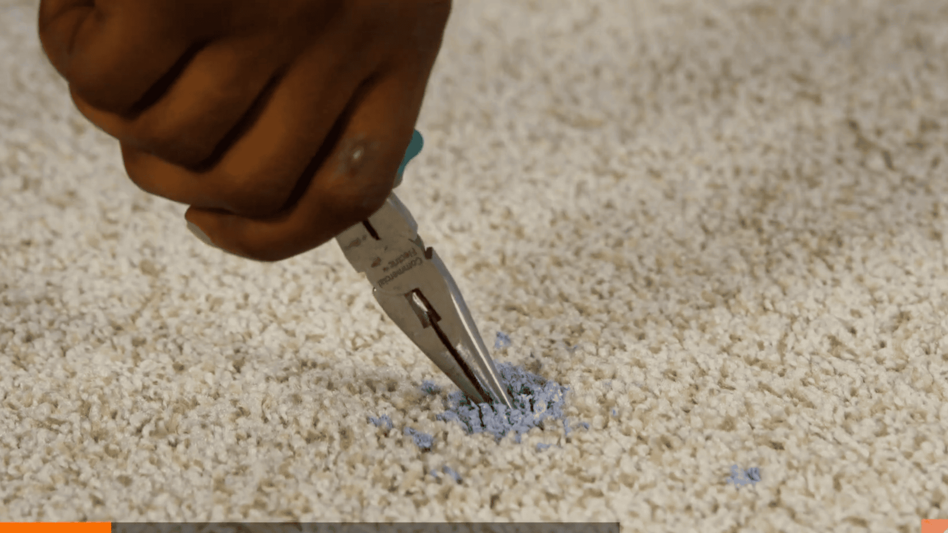 pliers being used to pull out dried paint clumps from light colored carpet fibers
