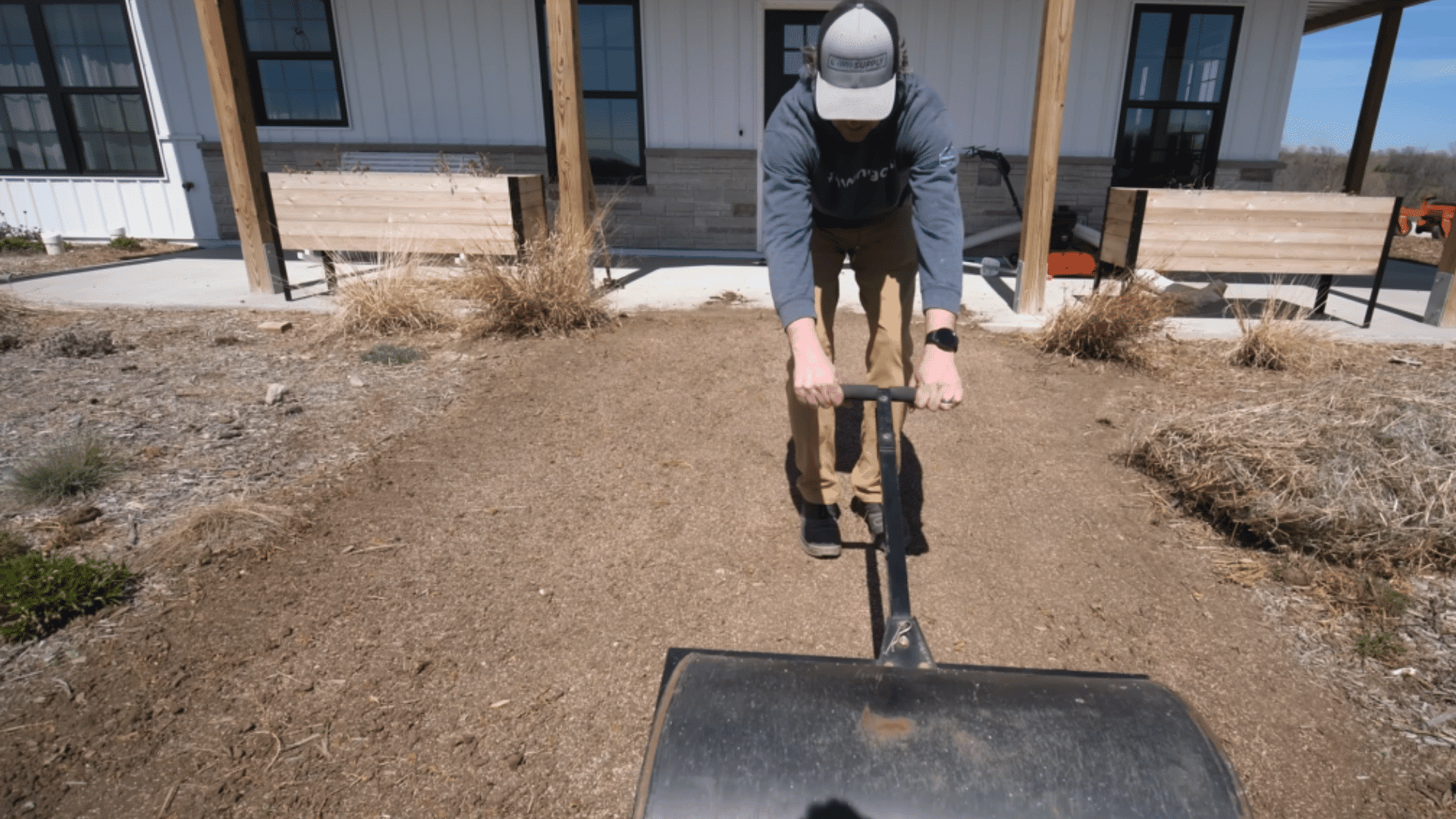 pressing soil gently with roller to secure grass seeds into the ground