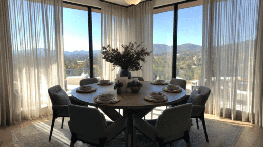 round dining table set for six with chairs large windows sheer curtains and scenic mountain view in bright room