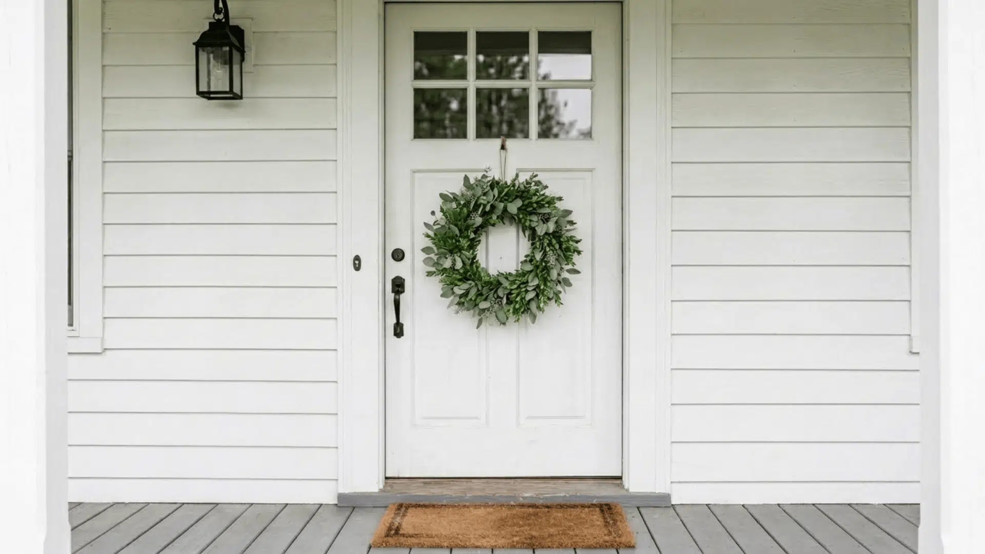 simple eucalyptus and boxwood greenery wreath on a white farmhouse front door in natural light