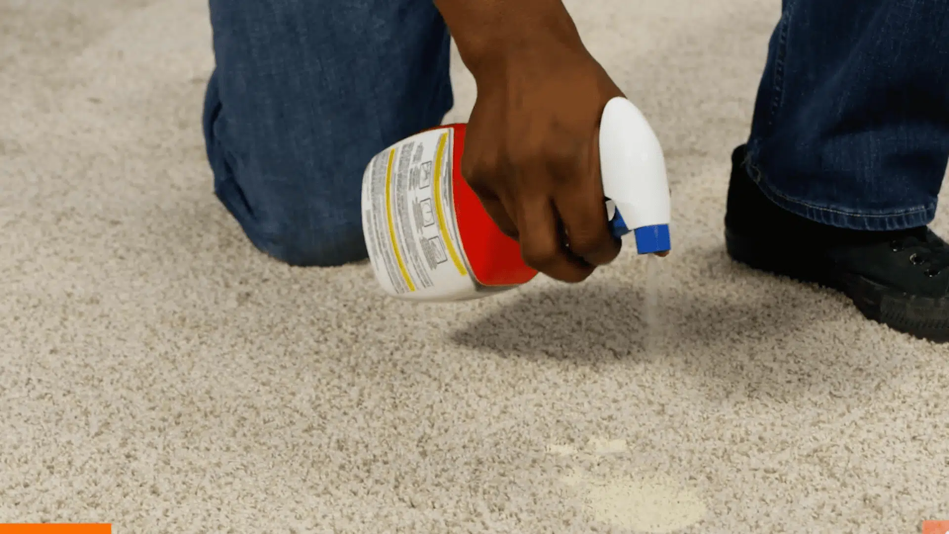spray bottle applying cleaning solution directly onto a paint stain on beige carpet