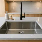 stainless steel undermount kitchen sink with clean empty basin and black faucet on modern countertop
