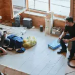 Two people taking a break in a partially renovated wooden room with tools and materials scattered around