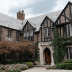 tudor revival house exterior with steep roof half timbering brick walls and arched entry surrounded by greenery