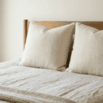 two large euro shams in herringbone pattern placed on a bed with wooden headboard and neutral linen bedding