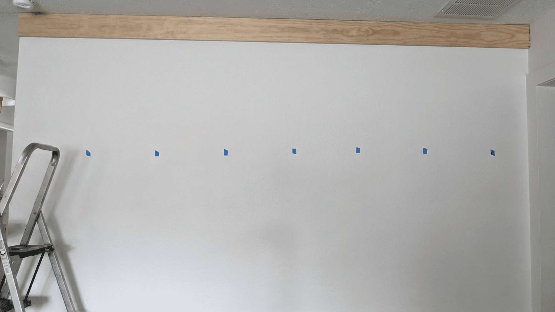 wall with blue painter's tape marking the spots for hanging items
