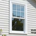 white framed double hung window on light siding exterior wall with visible trim and reflected trees in glass panes
