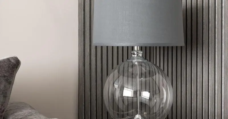 Modern glass table lamp with grey shade on striped wall background