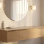 Modern bathroom with round mirror, wall sconces, and wooden vanity under soft natural light