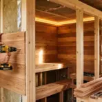 a person installs cedar panels for a diy sauna with a cordless drill; tools and heater nearby