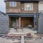 House extension under construction with exposed brick walls and unfinished steel beams