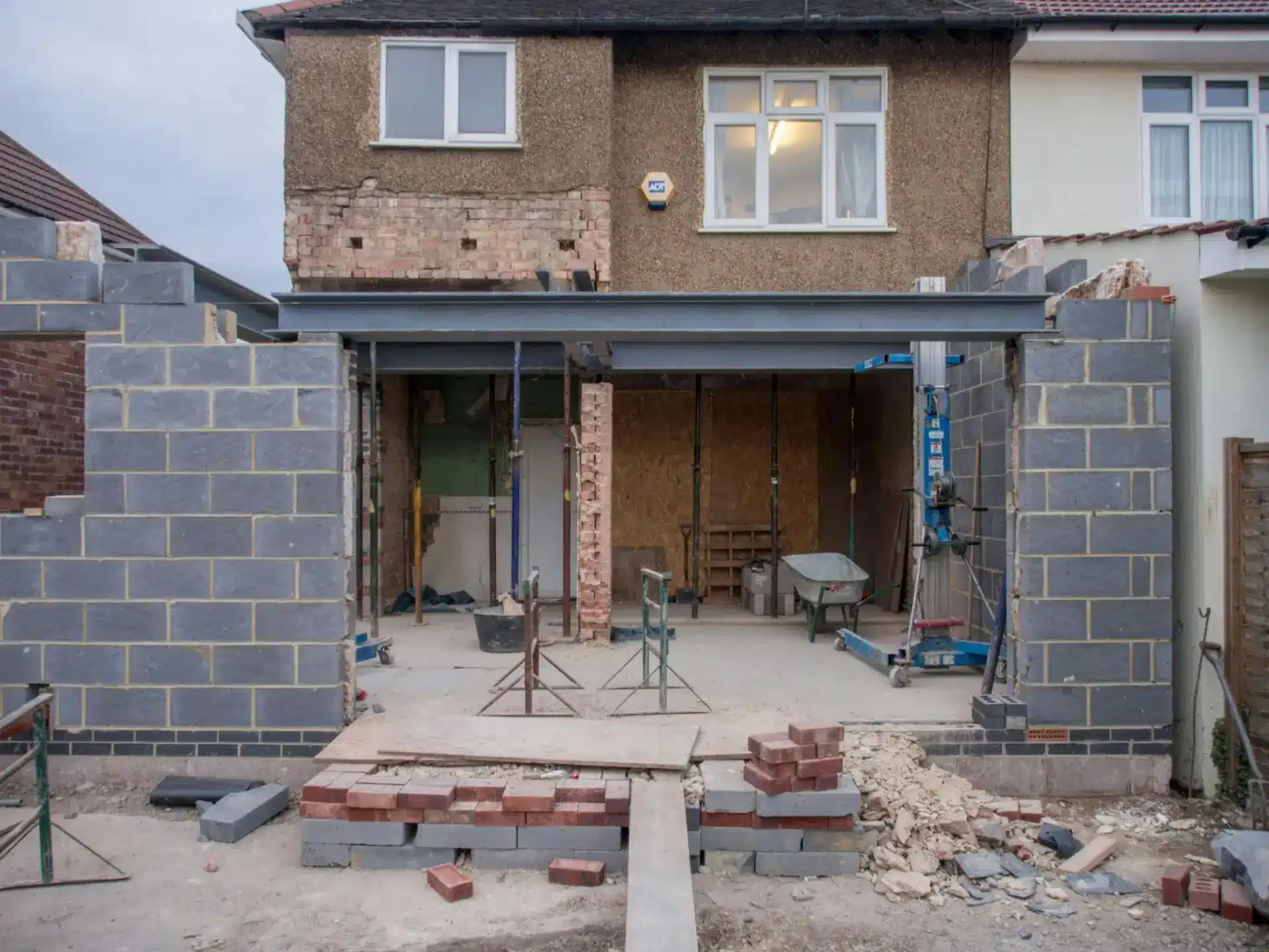House extension under construction with exposed brick walls and unfinished steel beams