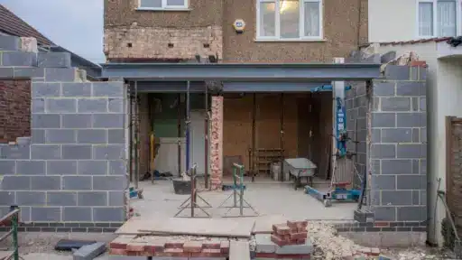 House extension under construction with exposed brick walls and unfinished steel beams