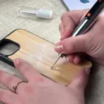 Hand engraving floral design on wooden phone case with electric engraving pen