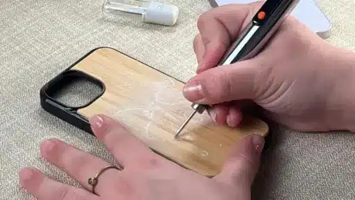 Hand engraving floral design on wooden phone case with electric engraving pen