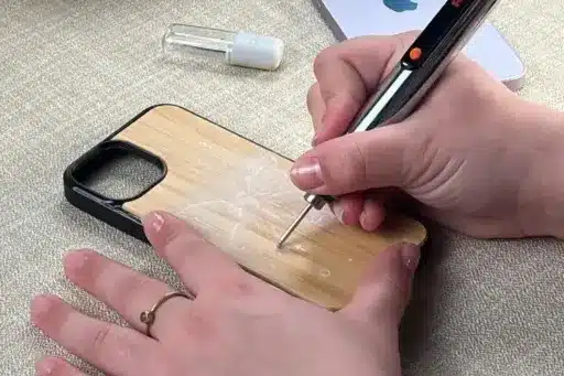 Hand engraving floral design on wooden phone case with electric engraving pen