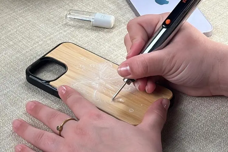 Hand engraving floral design on wooden phone case with electric engraving pen