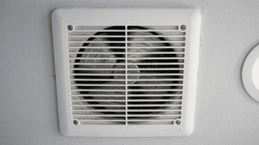 close-up of dusty bathroom exhaust fan cover with visible dirt buildup.