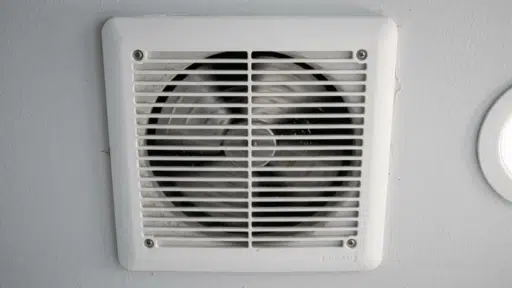 close-up of dusty bathroom exhaust fan cover with visible dirt buildup.