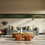 Modern living room with gray sofa, wooden coffee table, and large windows with indoor plants