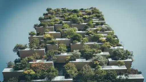 Modern building facade with abundant greenery on balconies under clear sky