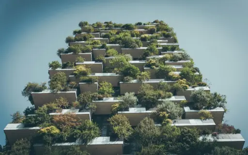 Modern building facade with abundant greenery on balconies under clear sky
