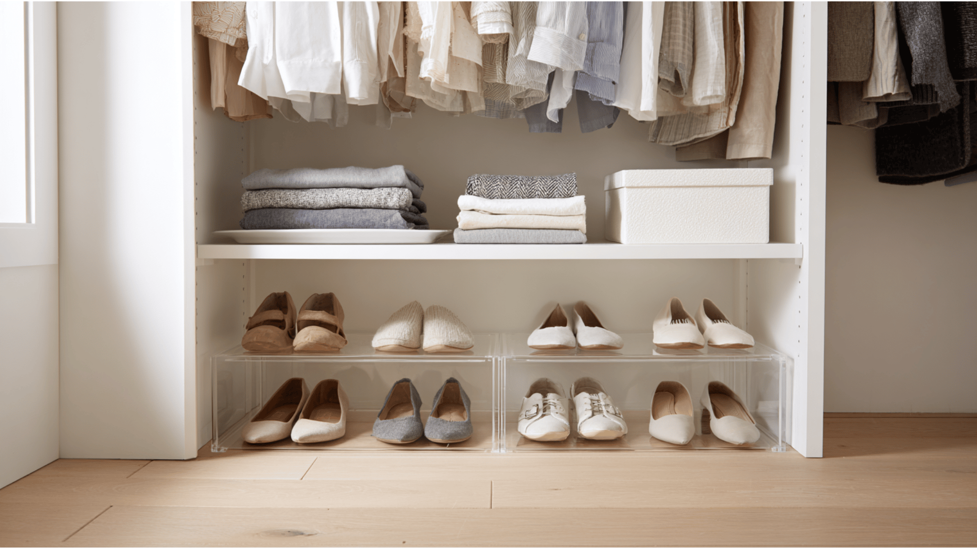 freestanding closet shelving unit elevated on furniture risers to create additional under-shelf shoe storage in a small closet.