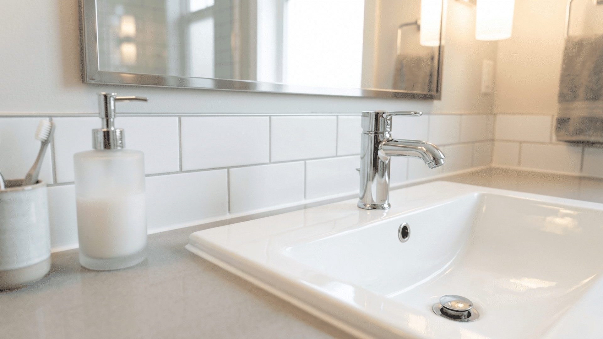 fresh white caulk applied neatly along the joint between a bathroom sink and a clean tiled wall