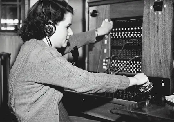 Woman operating vintage telephone switchboard in monochrome setting