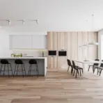 Modern kitchen with white cabinetry, black stools, wooden paneling, and large dining table under pendant lights