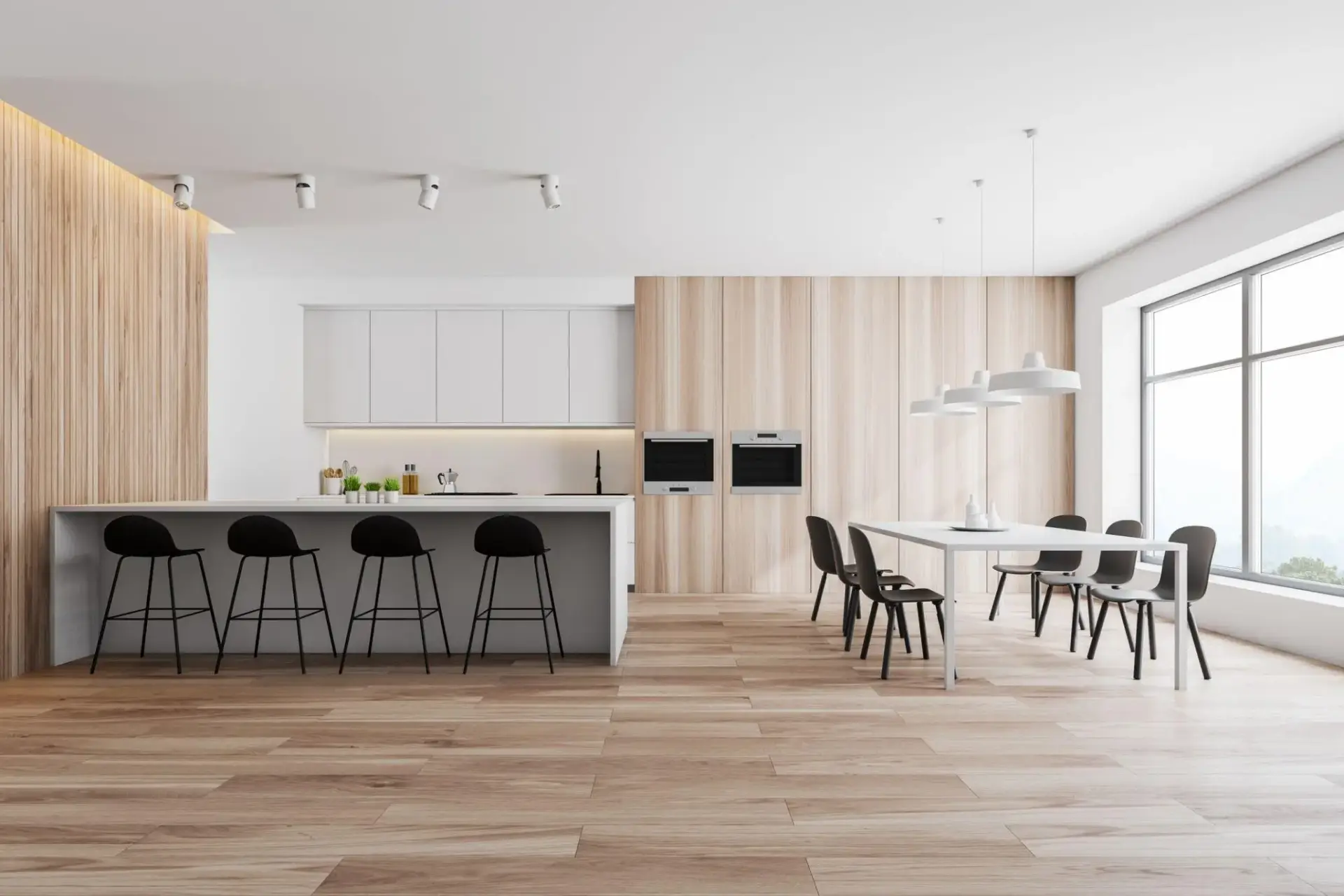 Modern kitchen with white cabinetry, black stools, wooden paneling, and large dining table under pendant lights