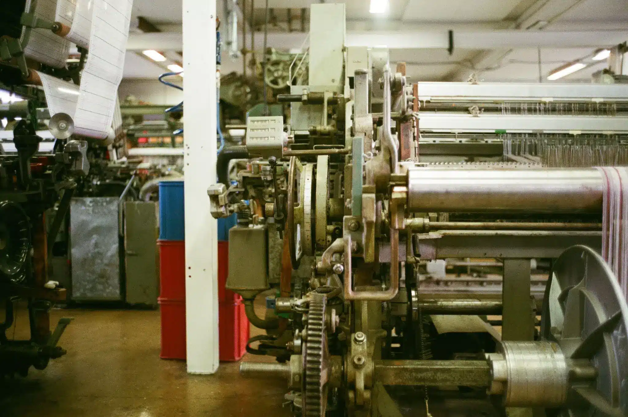 Industrial weaving machine with gears and rollers in a textile factory setting