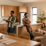 Group of friends socializing in a cozy kitchen with wooden cabinets and indoor plants