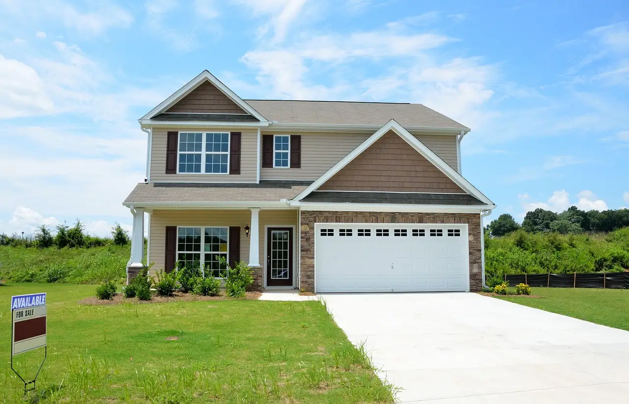 Two-story suburban house with attached garage and for sale sign in grassy yard