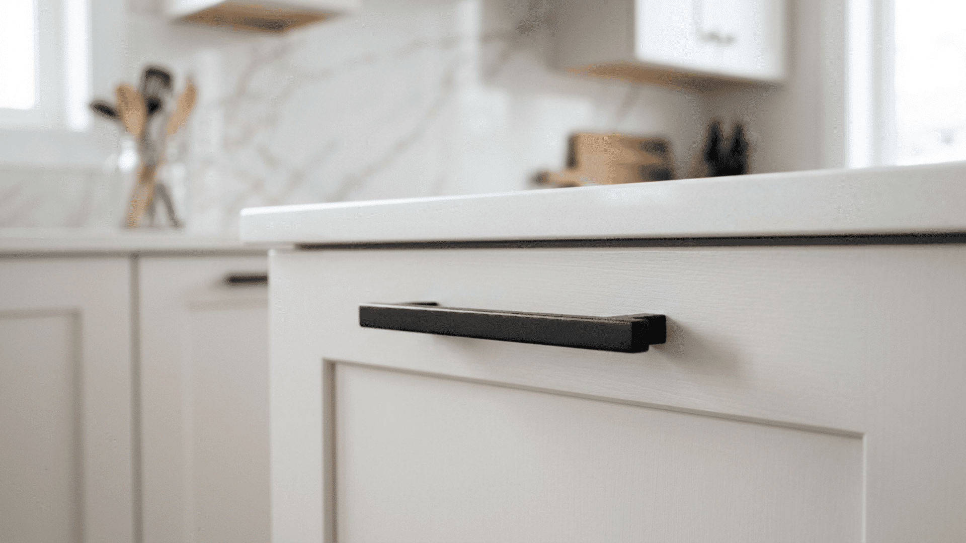 new matte black cabinet handle installed flush on a white kitchen cabinet door in a clean kitche