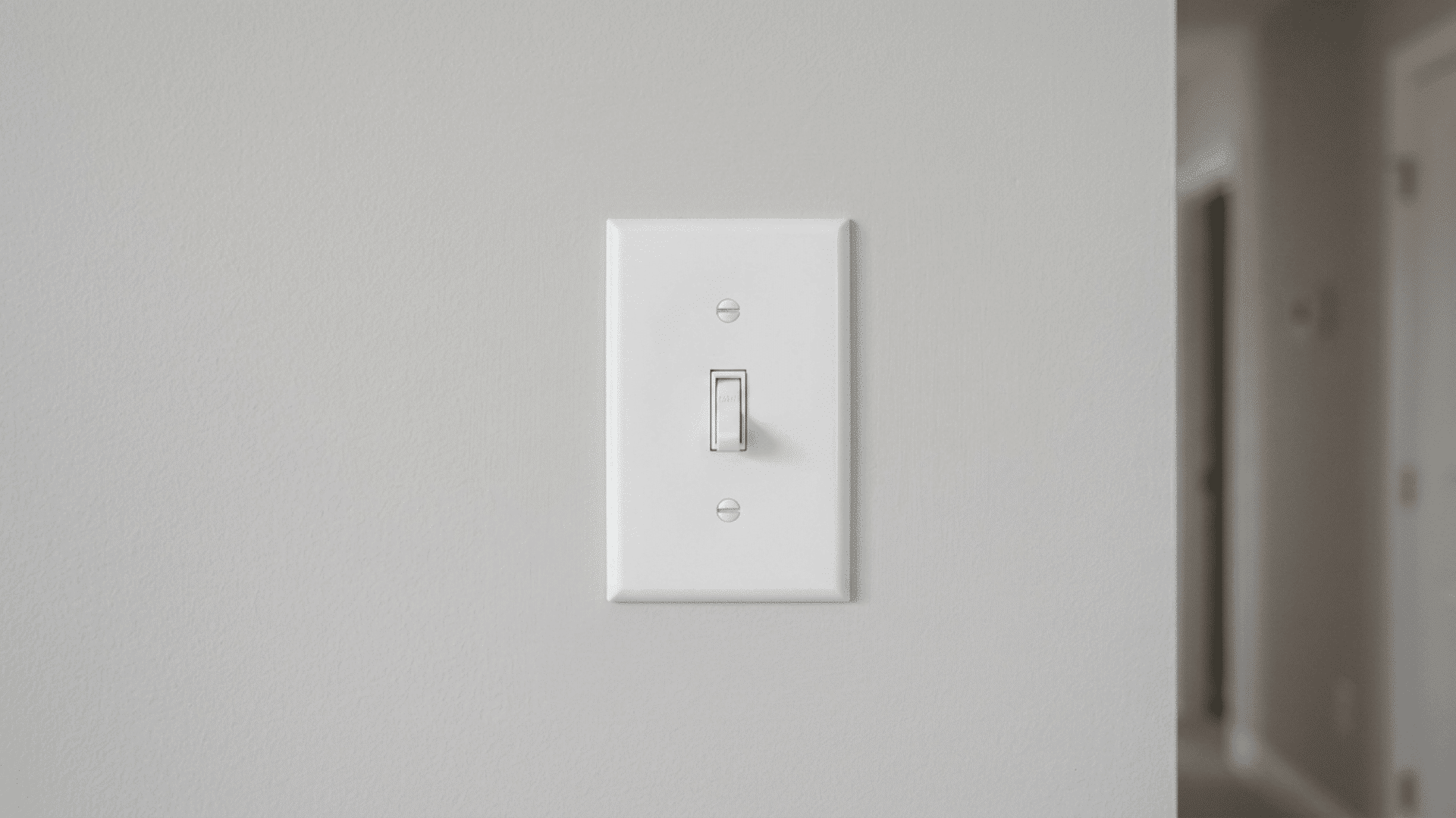 new white switch plate installed flush and straight on a smooth light gray interior wall