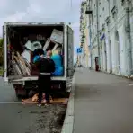 Moving truck parked on city street, man organizing contents, grey sky overhead