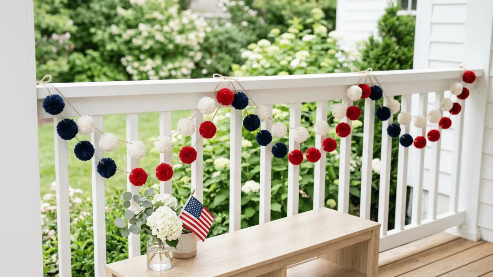 pom pom garland in red white blue draped across shelf adding soft and simple festive look