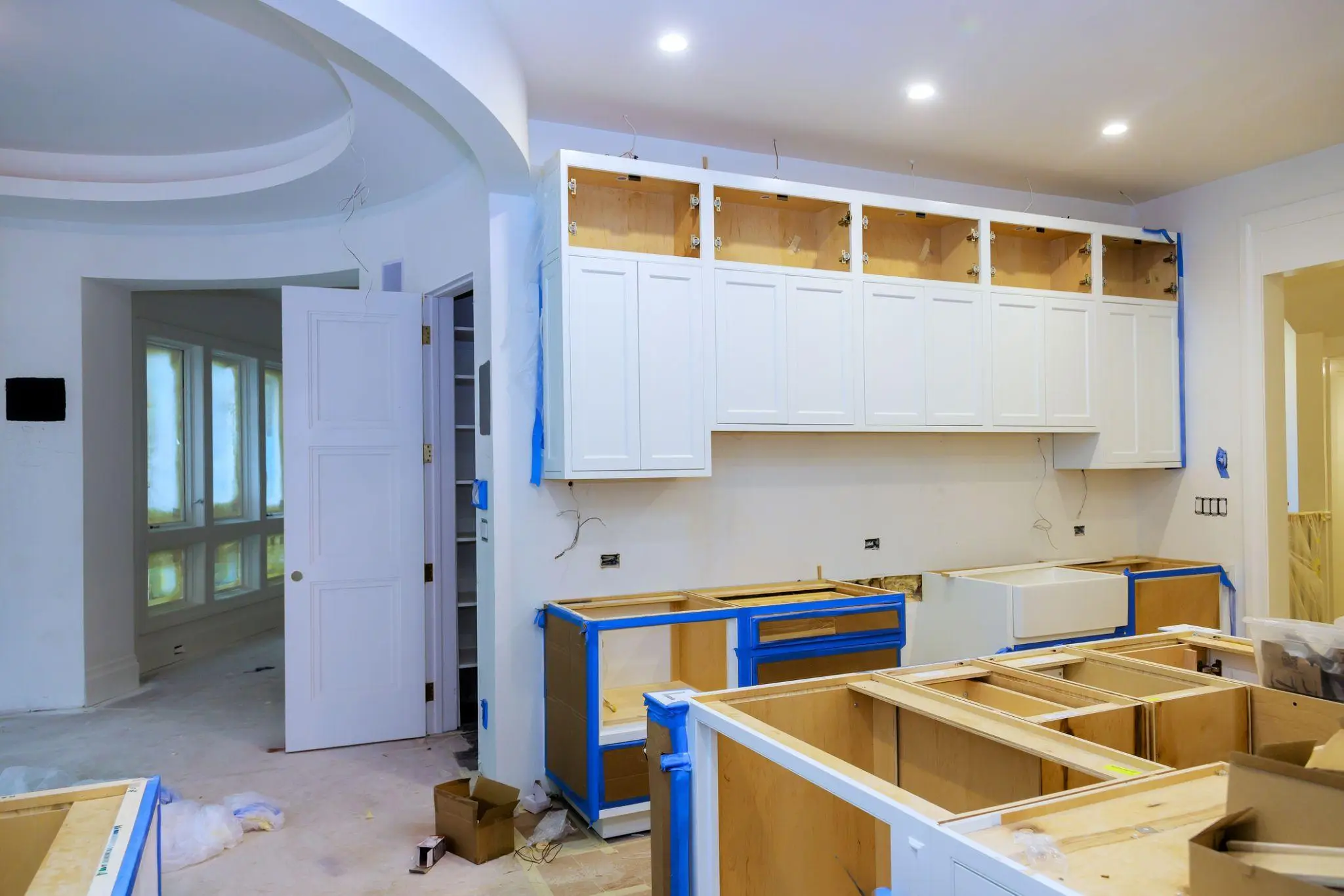 White kitchen cabinets being installed in a home renovation project with open boxes nearby