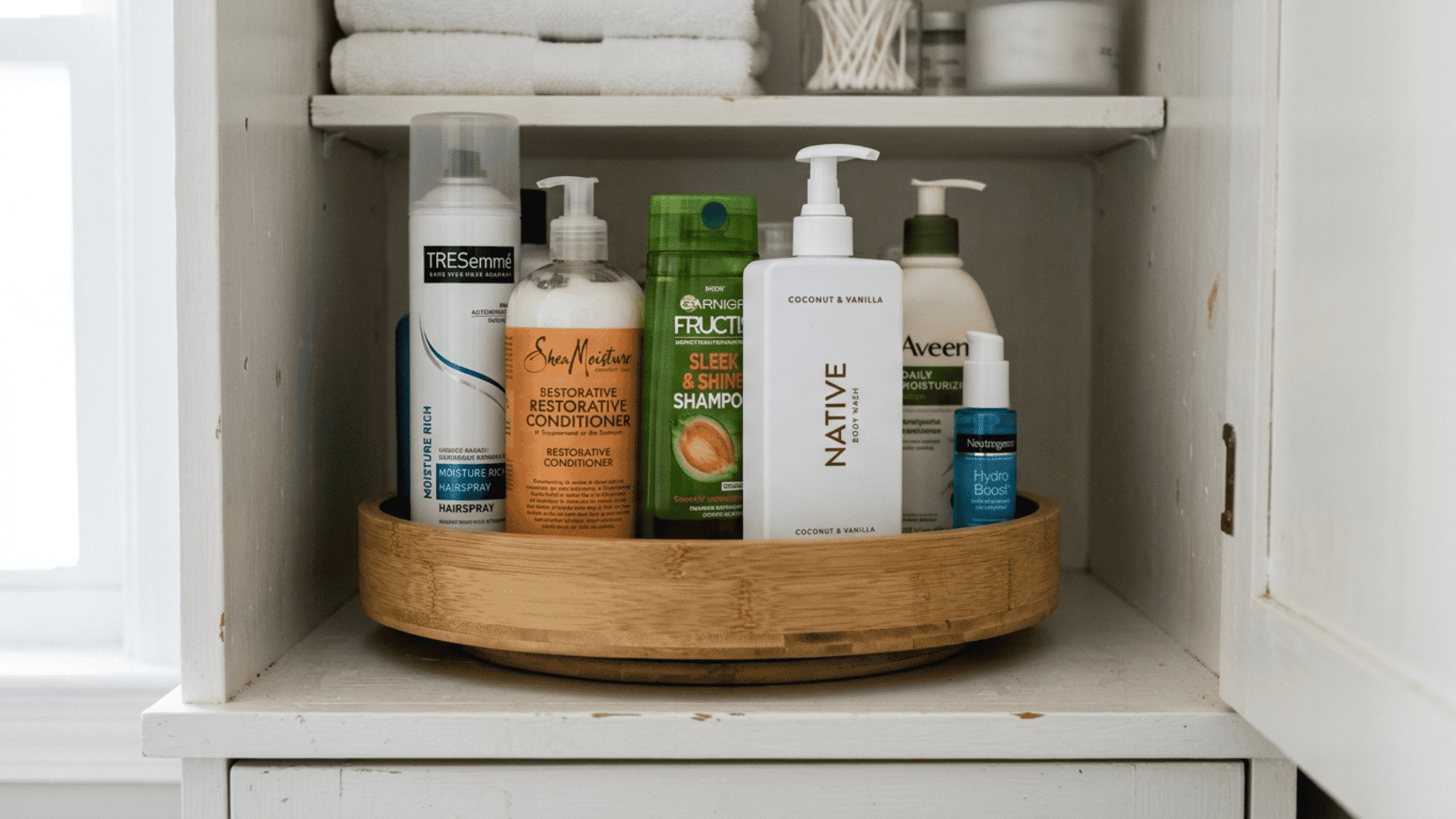 rotating tray inside a bathroom cabinet holding tall bottles of lotion hairspray and conditioner neatly arranged