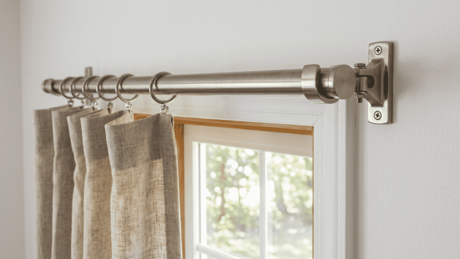 side angle view of brushed nickel curtain rod mounted above window with linen curtains partially visible hanging down