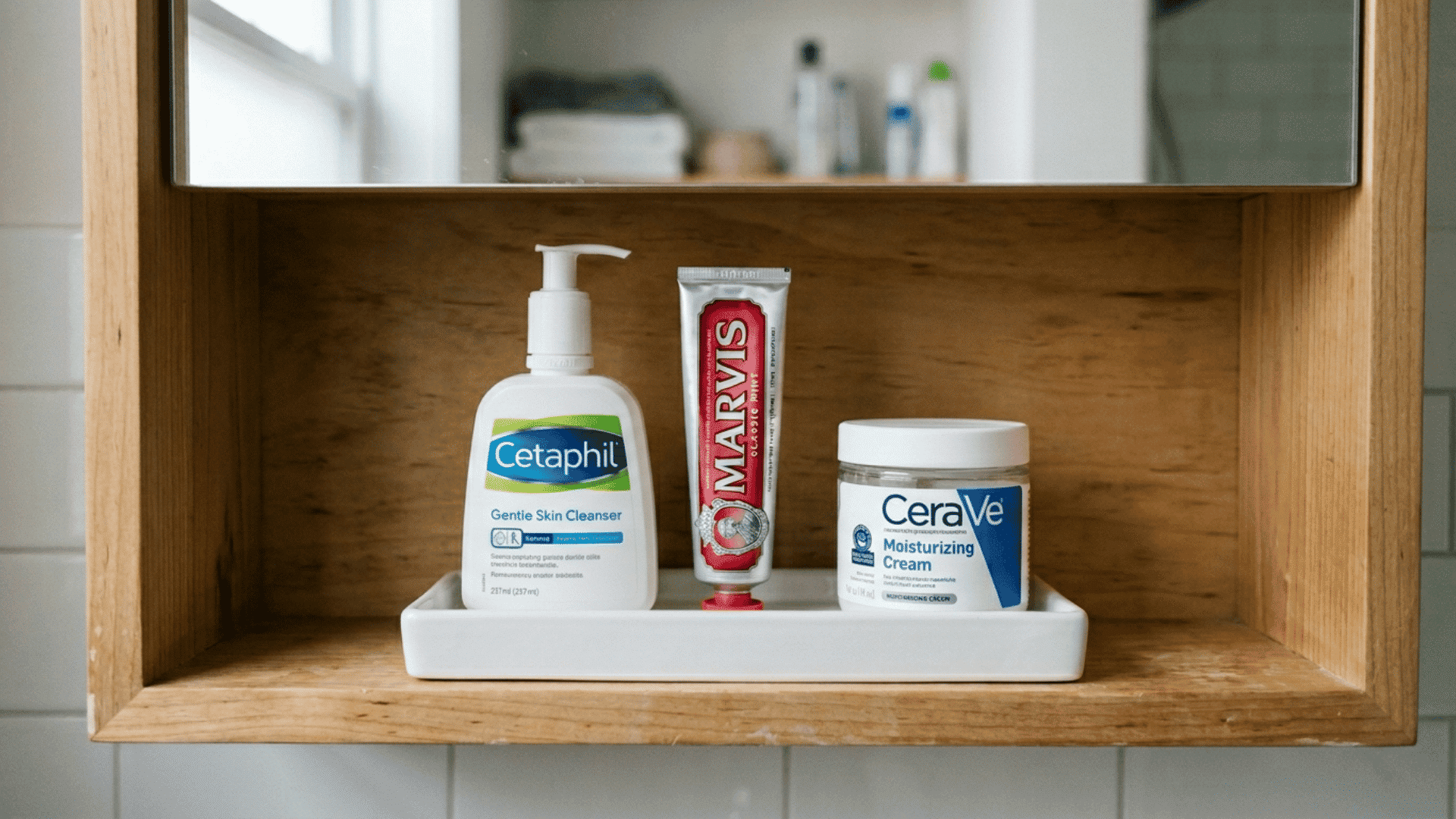 small white tray at the front of a bathroom cabinet shelf holding face wash toothpaste and moisturizer neatly together