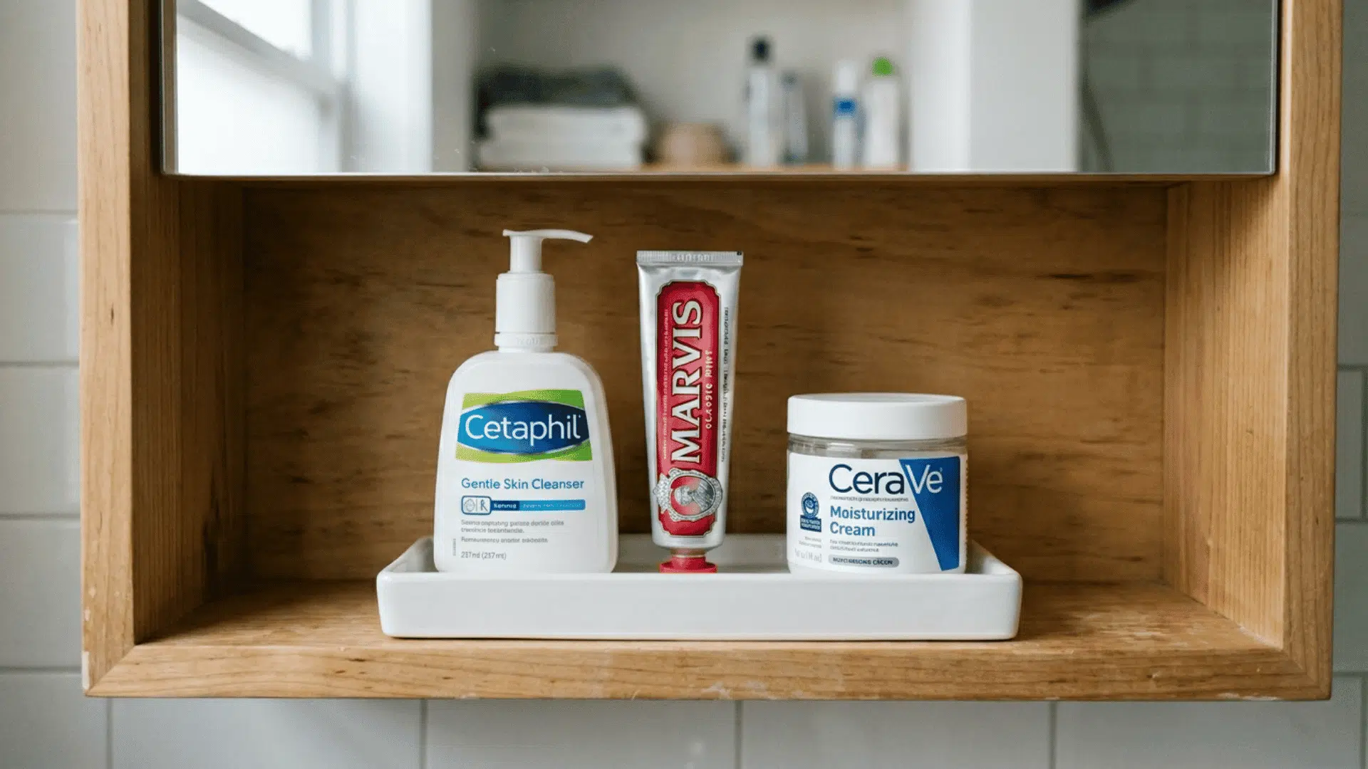 small white tray at the front of a bathroom cabinet shelf holding face wash toothpaste and moisturizer neatly together