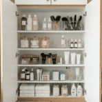 the inside of a bathroom cabinet with neatly arranged toiletries, brushes, and skincare products in clear bins.