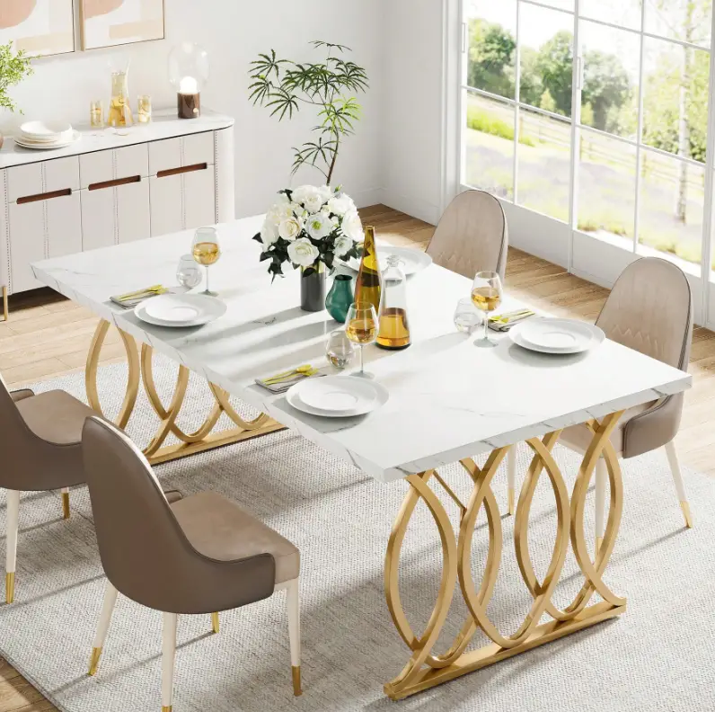 White dining table with gold legs in bright dining room, set with plates and wine glasses